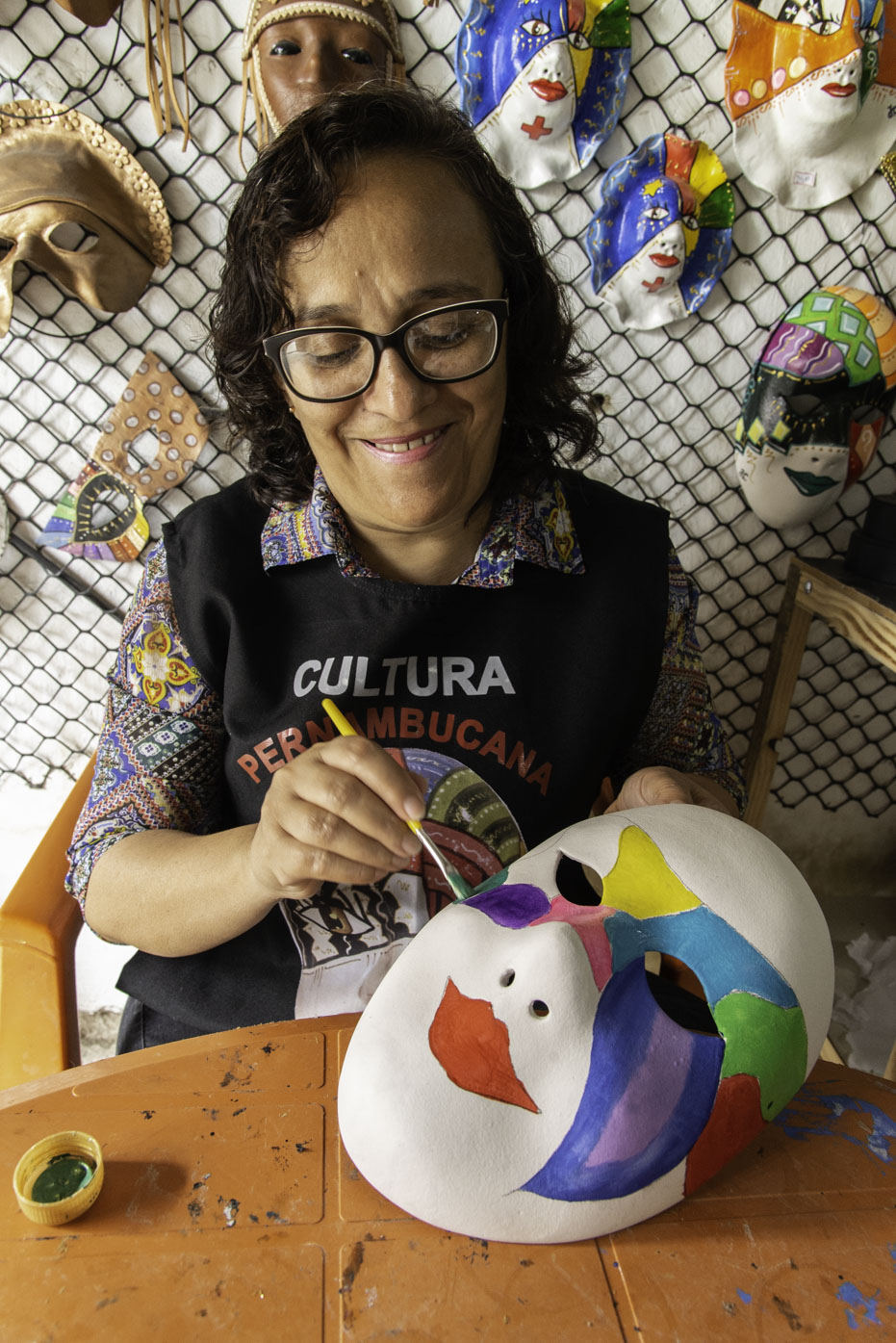 Maria Josileide dos Santos, pintando com tinta PVA, máscaras de papa-angu feitas com a técnica de Papier collé no seu Ateliê em Bezerros, PE. Dezembro de 2019.